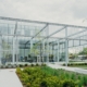 Cloudy sky and grey building surrounded by green gardens and shops